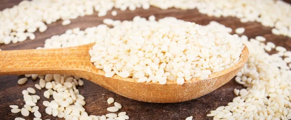 Sesame seeds with spoon on rustic board, healthy nutrition concept — Stock Photo, Image