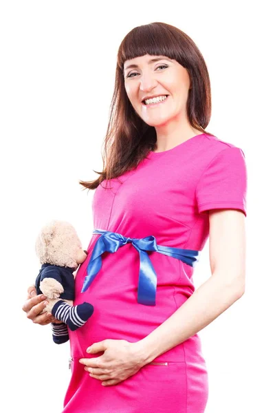 Leende kvinna i gravid klänning och hålla nallebjörn på hennes mage, förväntar sig för nyfödda koncept — Stockfoto