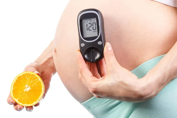 Pregnant woman holding fresh orange and glucometer with result of sugar level, diabetes and healthy nutrition during pregnancy — Stock Photo, Image