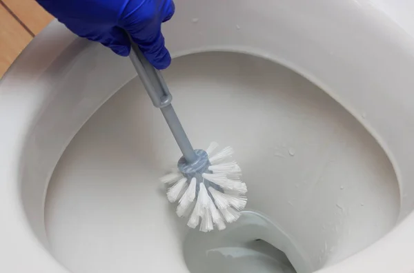 Main de femme en gant nettoyage cuvette de toilette, concept de tâches ménagères — Photo