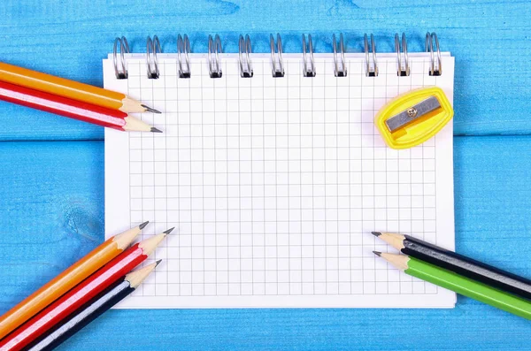 Πολύχρωμα μολύβια, ξύστρα και σημειωματάριο στα διοικητικά συμβούλια, σχολικά αξεσουάρ, πίσω στο σχολείο έννοια — Φωτογραφία Αρχείου