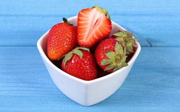 Fresas frescas frutas en tazón acostado sobre tablas azules, concepto de postre saludable — Foto de Stock