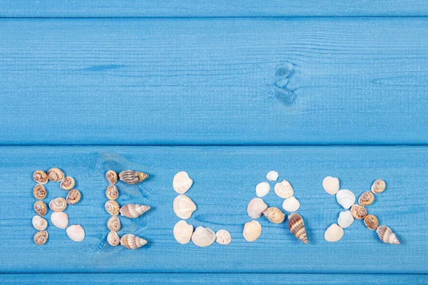 Palavra relaxar feito de conchas, conceito de hora de verão, espaço de cópia para texto em placas — Fotografia de Stock