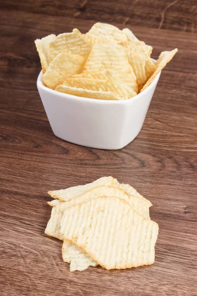 Patatas fritas saladas en cuenco de vidrio blanco a bordo, concepto de comida poco saludable —  Fotos de Stock
