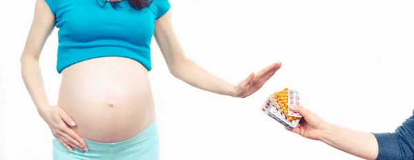 Woman in pregnant making stop gesture in front of medical tablets, reduction of using pharmaceuticals in pregnancy — Stock Photo, Image
