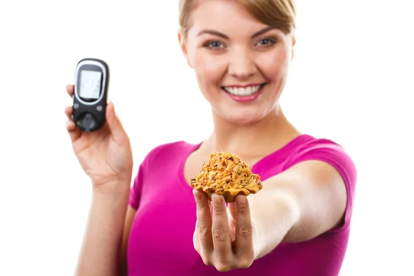 Woman holding glucometer and fresh cupcake, measuring and checking sugar level — Stock Photo, Image