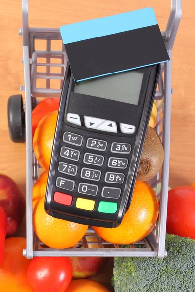 Maksupäätteen kontaktiton luottokortti ja hedelmiä ja vihanneksia — kuvapankkivalokuva