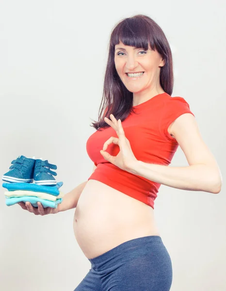 Vintage foto, Donna incinta mostrando segno ok e tenendo i vestiti per il neonato — Foto Stock