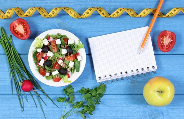 Ελληνική σαλάτα με λαχανικά, μετροταινία και Σημειωματάριο (Notepad), υγιεινή διατροφή και αδυνάτισμα έννοια — Φωτογραφία Αρχείου