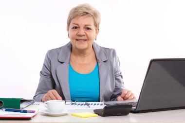 Ofis masasında çalışan yaşlı bir iş kadını