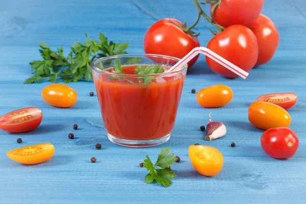 Verse gezonde tomatensap en fruit met specerijen op blauwe bord — Stockfoto