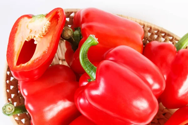 Hoop van rode paprika's in rieten mand op witte achtergrond, gezonde voeding — Stockfoto