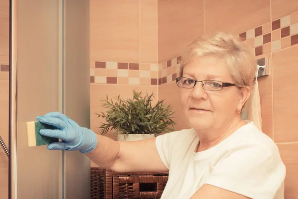 Vieille femme âgée essuyant verre de douche, nettoyage de la maison et des tâches ménagères concept — Photo
