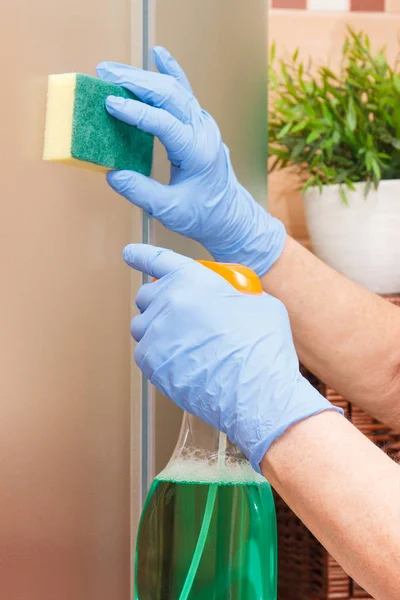 Рука пожилой женщины уборка стеклянный душ с использованием губки и моющего средства, домашние обязанности концепции — стоковое фото
