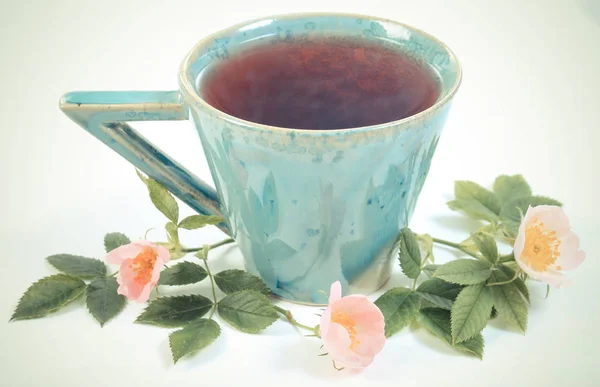 Jahrgangsfoto, Tasse heißen Tee und Wildrosenblume — Stockfoto