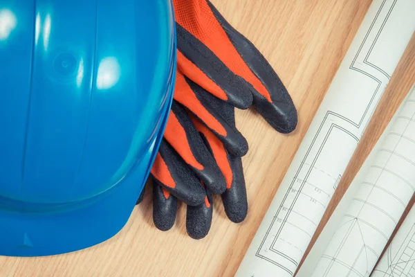 Rolls of electrical blueprints, protective blue helmet and gloves — Stock Photo, Image