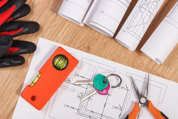 Home keys with electrical drawings, protective gloves and orange work tools, concept of building home