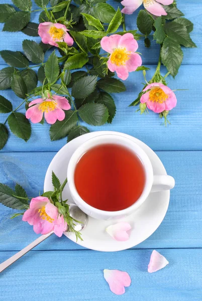 Tasse Tee und Wildrosenblume auf Brettern — Stockfoto