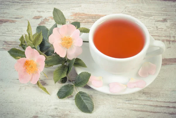 Vintage Fotoğraf, fincan çay ve rustik ahşap arka plan üzerinde yabani gül çiçek