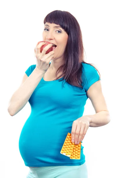 Винтажное фото, счастливая женщина в беременной есть свежее яблоко и проведение медицинских таблеток или добавок — стоковое фото