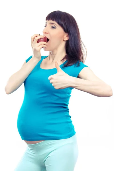 Happy těhotná žena jíst jablko a ukazuje palec nahoru, zdravé potraviny v těhotenství — Stock fotografie