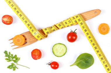 Ahşap çatal santimetre ve beyaz arka plan üzerinde taze sebze ile zayıflama ve sağlıklı beslenme kavramı