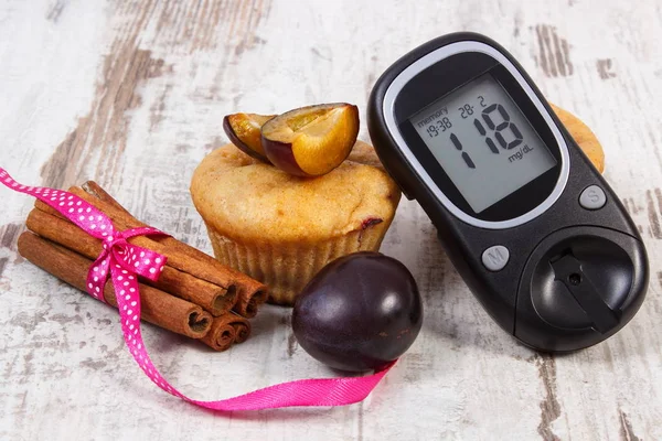 Glucose meter, muffins met pruimen en kaneelstokjes op rustieke bestuur, diabetes en heerlijk dessert concept — Stockfoto