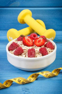 Yulaf gevreği veya yulaf ezmesi meyve, mezura ve halter, sağlıklı, sportif yaşam tarzı ve beslenme kavramı