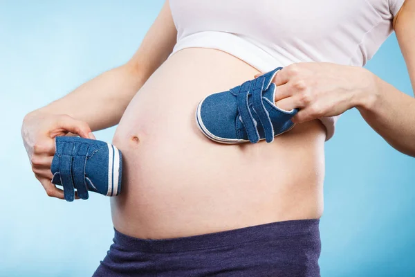 Vrouw in zwanger met baby schoenen, verwacht voor baby — Stockfoto