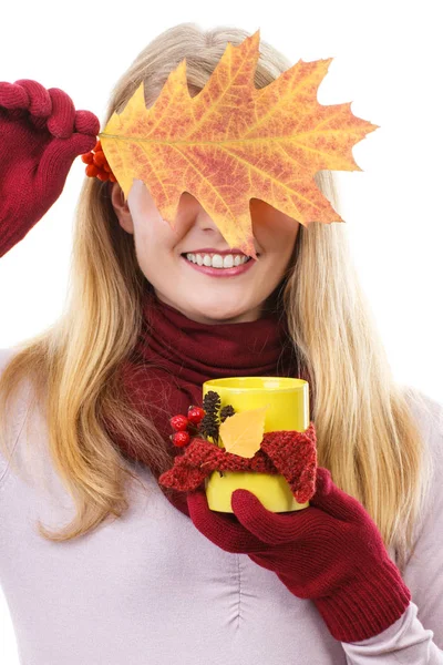 Chica sonriente en guantes sosteniendo taza decorada de té y hoja otoñal — Foto de Stock