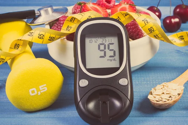 Glucose meter, oat flakes with fruits, dumbbells and tape measure, concept of diabetes, slimming and sporty lifestyle