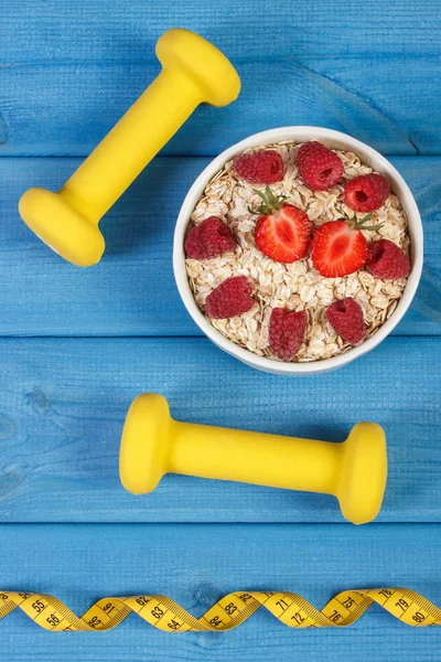 Fresh oatmeal with strawberries and raspberries, centimeter and dumbbells, healthy lifestyle and nutrition — Stock Photo, Image