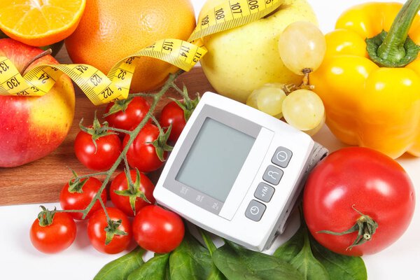 Монитор артериального давления, свежие спелые фрукты с овощами и лентой, здоровый образ жизни
