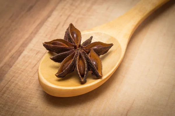 Зоряний аніс з дерев'яною ложкою на дерев'яній дошці, приправа для приготування їжі або випічки — стокове фото