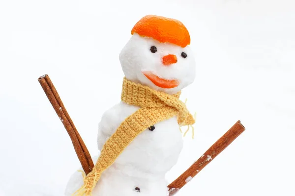 Bonhomme de neige décoré avec écharpe et écorce de mandarine sur fond blanc — Photo