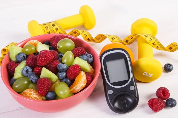 Ensalada de frutas frescas, glucosímetro para controlar el nivel de azúcar, centímetros y mancuernas, concepto de diabetes — Foto de Stock