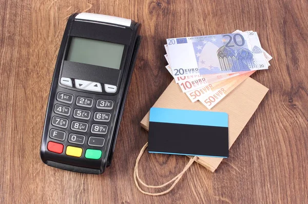 Terminal de pago con tarjeta de crédito, monedas en euros y bolsa de compras de papel, concepto de pago por compras — Foto de Stock