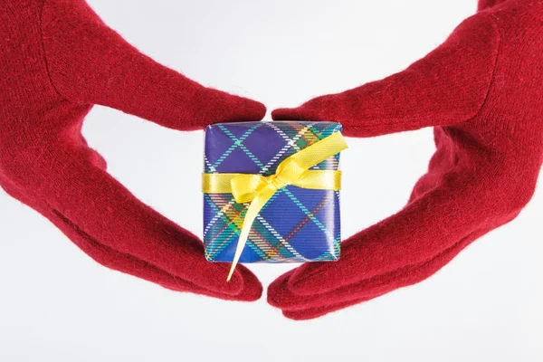 Hände einer Frau in roten Handschuhen mit Geschenk für Weihnachten oder andere Feierlichkeiten — Stockfoto