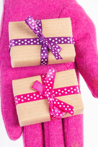 Το χέρι της γυναίκας σε ροζ γάντια με δώρα για τα Χριστούγεννα ή άλλη γιορτή — Φωτογραφία Αρχείου
