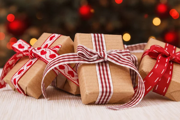Τυλιγμένα δώρα με κορδέλες και χριστουγεννιάτικο δέντρο με φώτα στο παρασκήνιο — Φωτογραφία Αρχείου
