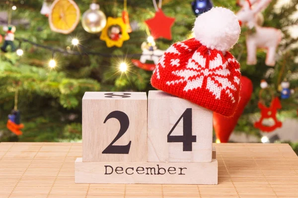 Datum 24 December med mössa och festlig träd med dekoration i bakgrunden, julafton tid koncept — Stockfoto