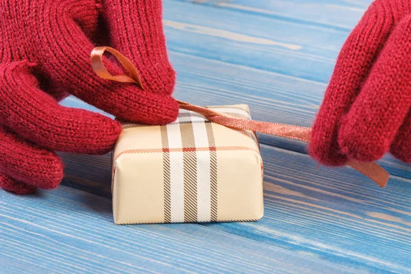 在包装的礼物为圣诞节或其他庆祝活动的手套的女人手上 — 图库照片