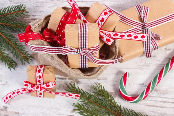 Δώρα με κορδέλες για τα Χριστούγεννα ή του Αγίου Βαλεντίνου στη Γιούτα σάκο και έλατο κλαδιά — Φωτογραφία Αρχείου