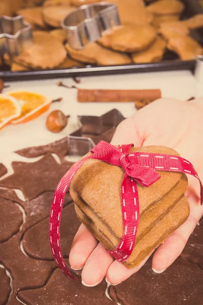 Foto Vintage, Mano di donna con pan di zenzero o biscotti per il periodo natalizio e accessori per la cottura — Foto Stock