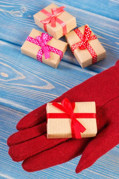 Main de femme en gants de laine rouge avec des cadeaux pour Noël ou toute autre célébration — Photo