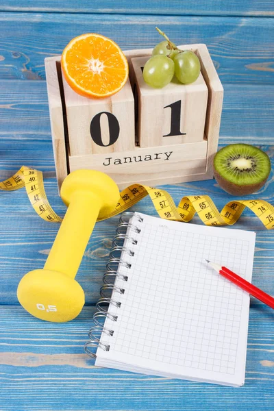 Cube calendar with date of 1 January, fruits, dumbbells and tape measure, new years resolutions — Stock Photo, Image