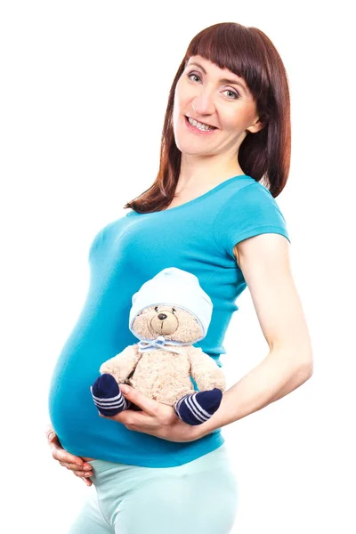 妊娠中で笑顔の女性が赤ちゃんを期待して、腹で子供のためグッズ テディベアを保持 — ストック写真