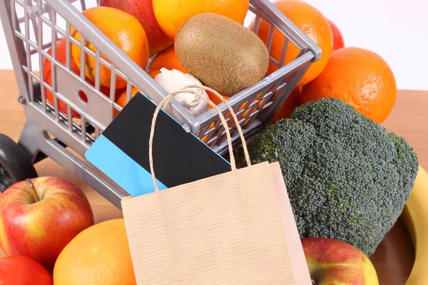 Бесконтактная кредитная карта, бумажный пакет и фрукты с овощами — стоковое фото