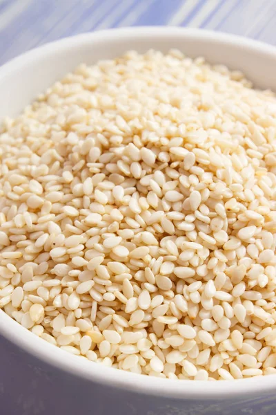 Heap of sesame seeds in white bowl on wooden boards — Stock Photo, Image