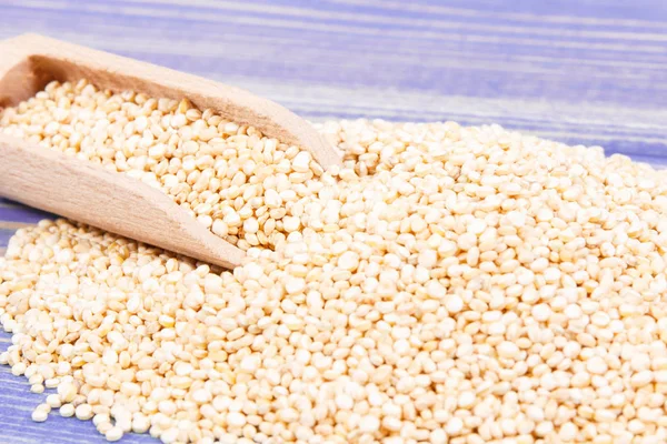 Σωρός από σπόρους quinoa με ξύλινη κουτάλα ως πηγή υγιών βιταμινών — Φωτογραφία Αρχείου